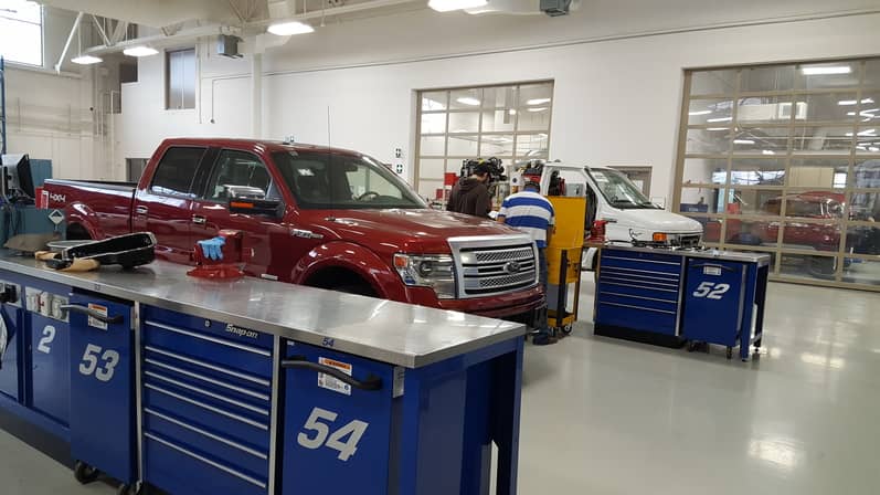 Students in garage working on red Ford truck